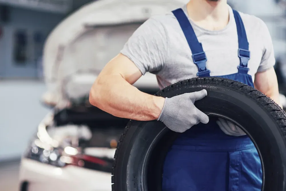 mechanic-holding-tire-tire-repair-garage-replacement-winter-summer-tires.webp